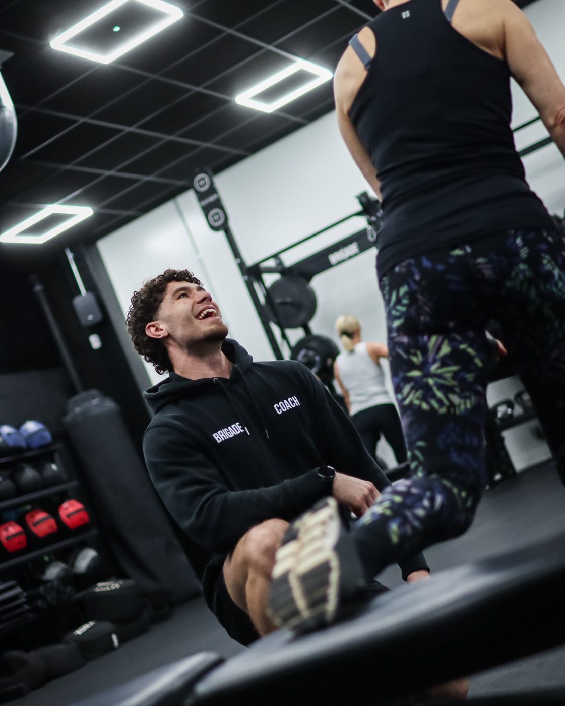 A Brigade coach laughing with a member mid-session