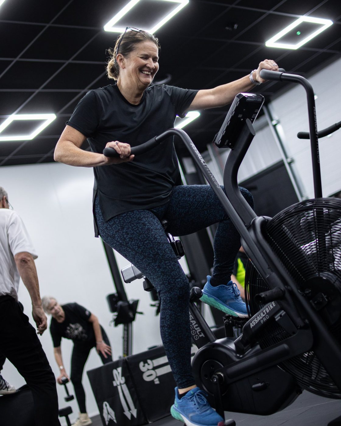 A Brigade member smiling mid-set on the assault bike
